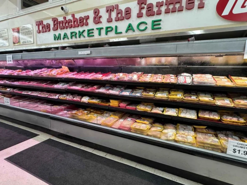 Fresh meat case stretching the length of the department under the store sign at Butcher & Farmer Market in Buckeye, AZ.