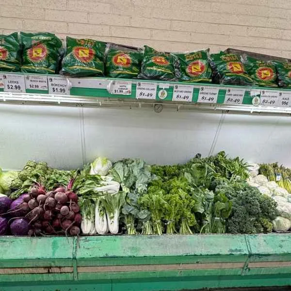Fresh greens, cabbage, cauliflower and vegetables on the produce stand, with chips displayed above at Butcher & Farmer Market in Buckeye, AZ.