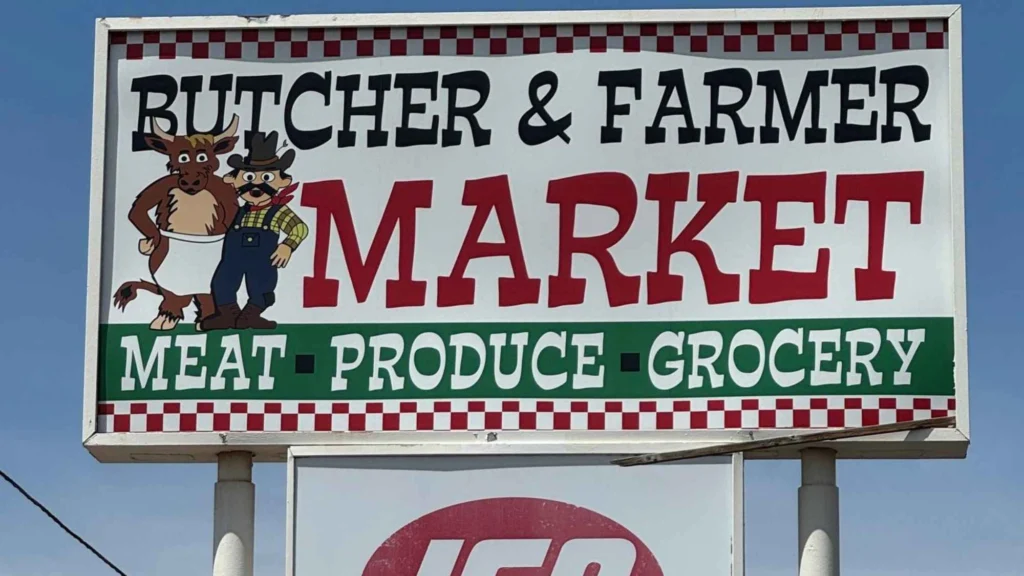 Butcher & Farmer Market pole sign reading Meat, Produce, Grocery, with the IGA logo in Buckeye, AZ.