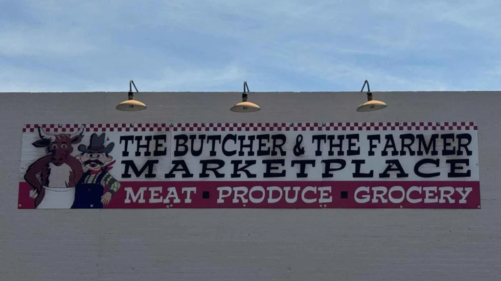 The Butcher & The Farmer Marketplace wall sign with gooseneck lights in Buckeye, AZ.