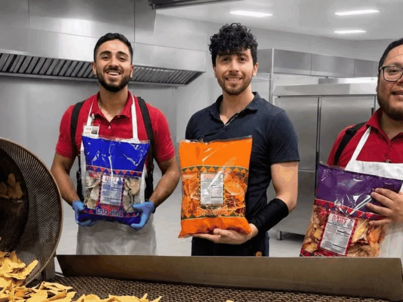 Doña Lupe Tortillería team holding bags of fresh tortilla chips in the kitchen at Del Sol in San Luis, AZ
