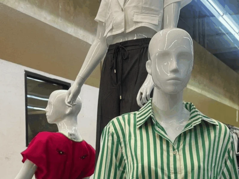 Mannequins wearing a striped button-up shirt and a red embroidered dress in the clothing department at Del Sol Market San Luis East in San Luis, AZ