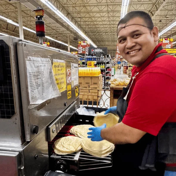 Smiling tortillería team member making fresh tortillas at Del Sol Market in San Luis, AZ