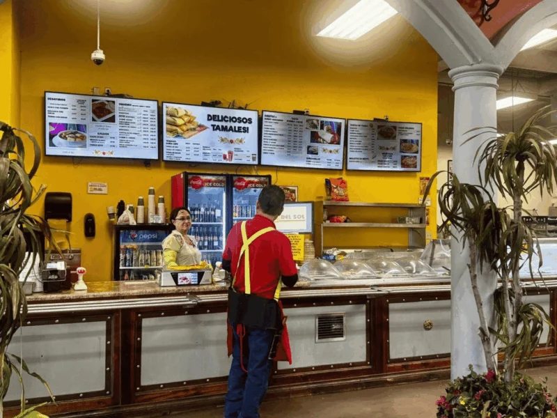 Team member at the restaurant counter with menu boards at Del Sol in Somerton, AZ