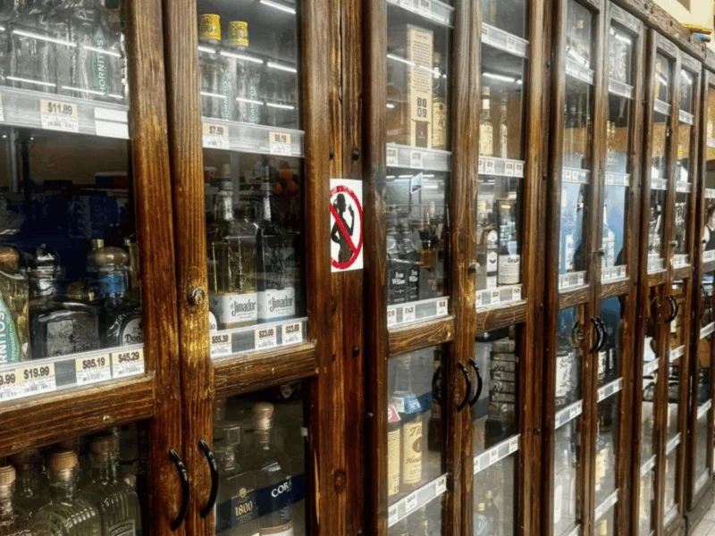 Wood-framed glass cases of wine and liquor in the liquor department at Del Sol on 16th Street in Yuma, AZ