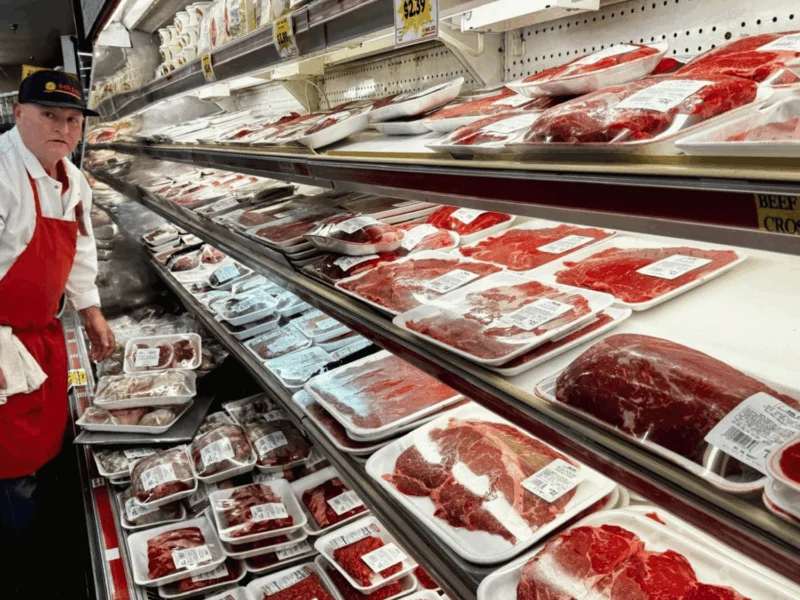 Butcher stocking fresh beef in the meat case at Del Sol on 16th Street in Yuma, AZ