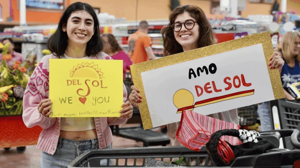 Smiling shoppers holding Amo Del Sol and Del Sol We Love You signs at Del Sol in the Yuma Foothills, AZ