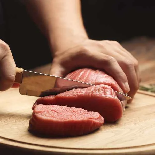 Butcher slicing a fresh beef roast into steaks