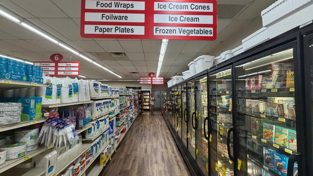 Aisle with paper plates and foil on one side and ice cream and frozen vegetables on the other at Food Town IGA in Eloy