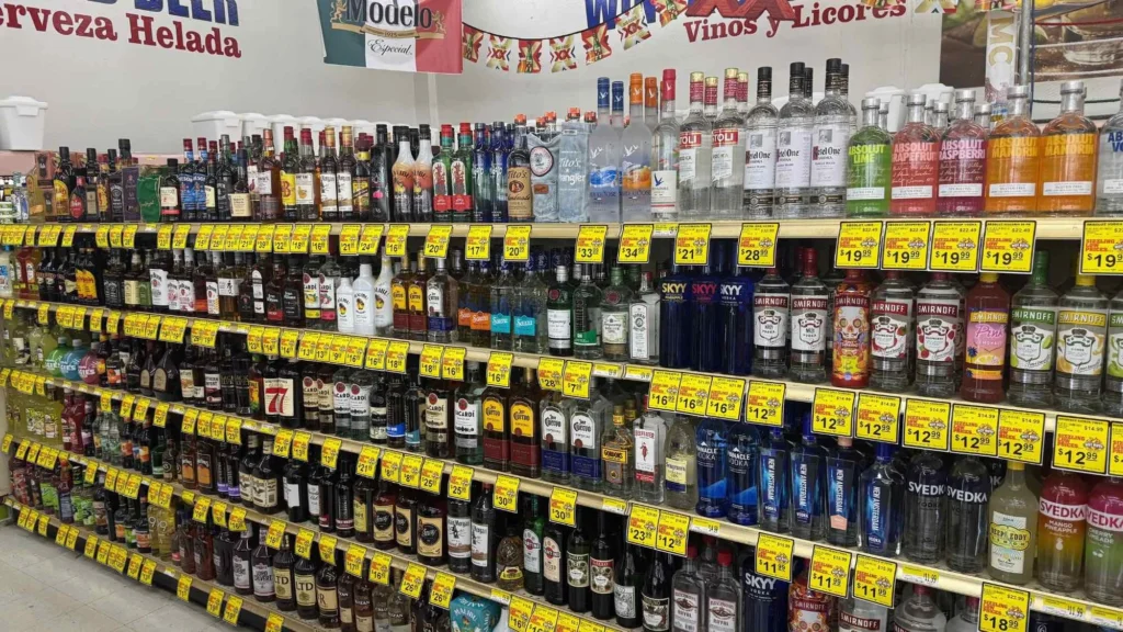 Wine and spirits aisle with tequila, vodka and whiskey on shelves under Vinos y Licores and Cerveza Helada signs