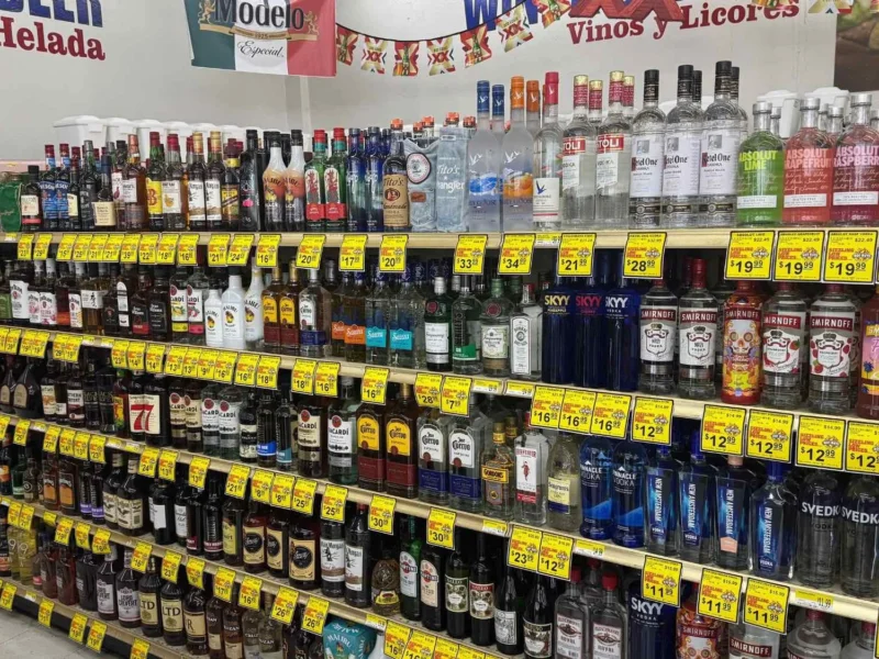 Wine and spirits aisle with tequila, vodka and whiskey on shelves under Vinos y Licores and Cerveza Helada signs