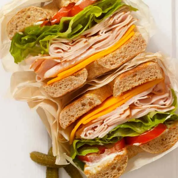 Deli sandwiches stacked with sliced ham, turkey, cheese, lettuce and tomato