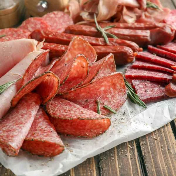 Sliced salami and cured deli meats on parchment paper