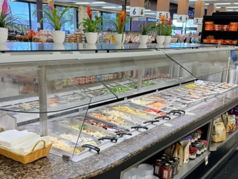 Full salad bar with fresh toppings under a glass sneeze guard