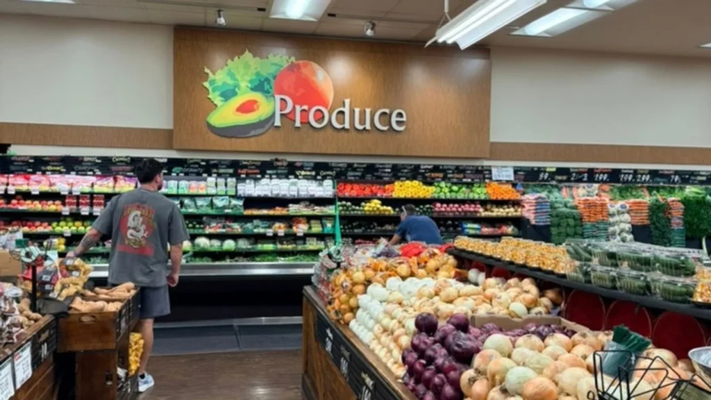 Produce department with a Produce sign, fresh vegetables and shoppers