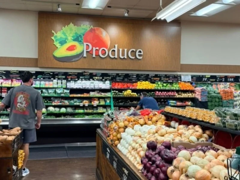 Produce department with a Produce sign, fresh vegetables and shoppers