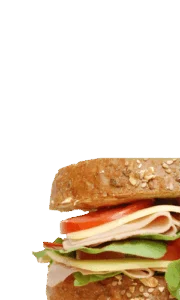 Deli sandwich with ham, turkey, cheese, lettuce and tomato on a whole grain bun