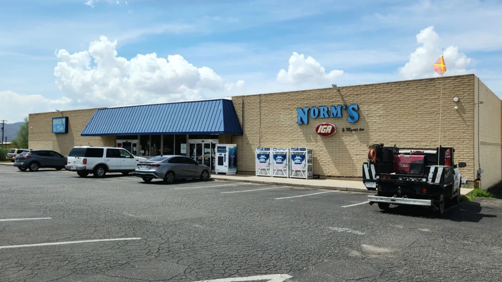 Norm's IGA storefront and parking lot under a blue sky