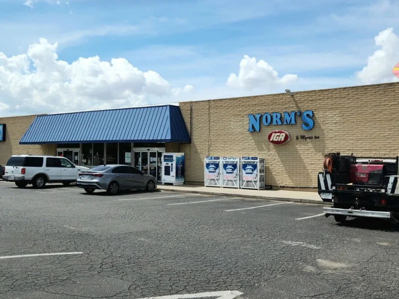 Norm's IGA storefront and parking lot under a blue sky