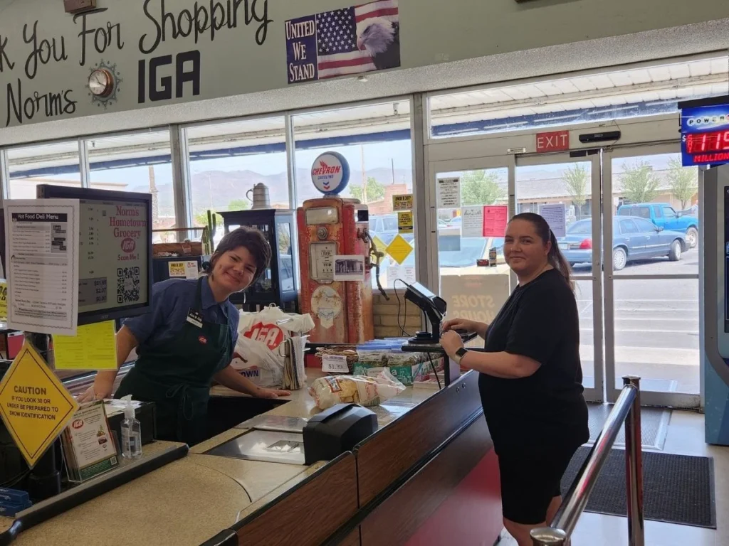 Cashiers helping shoppers at the Norm's IGA checkout lanes