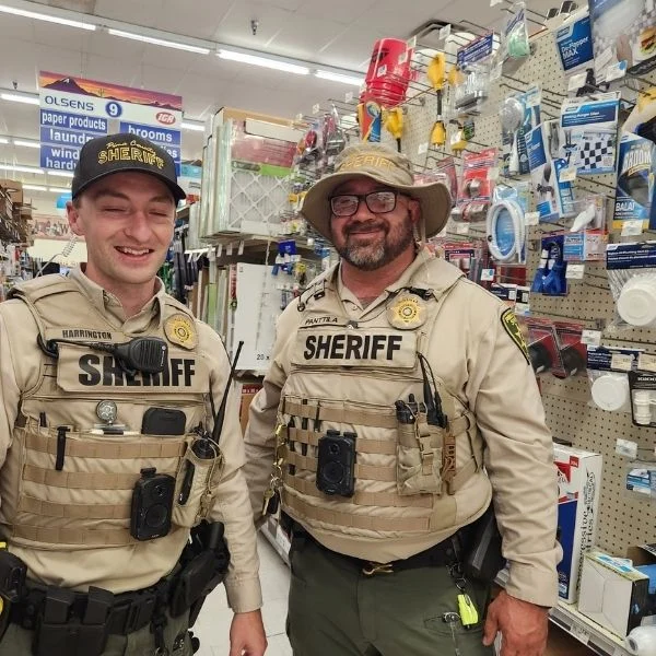 Two sheriff's deputies smiling inside Olsens Marketplace