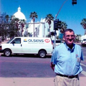 Historical photo of a man standing by an Olsens Marketplace van