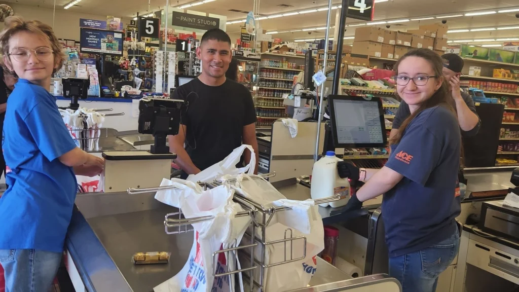 Olsens Marketplace cashiers helping a young customer at the checkout