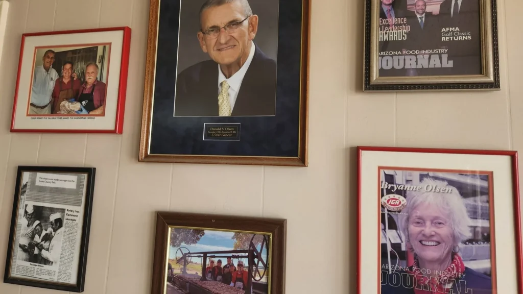 Wall of framed family photos and newspaper clippings at Olsens Marketplace