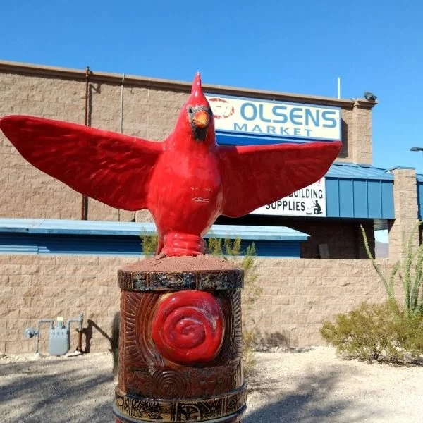 Red cardinal sculpture with outstretched wings outside Olsens Marketplace