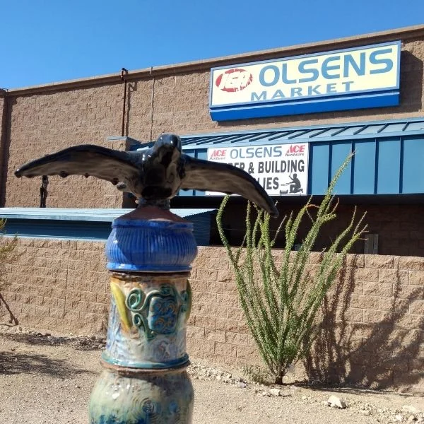 Black raven sculpture on a painted pedestal outside Olsens Marketplace