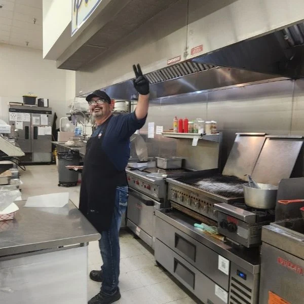 Olsens Patio Cafe cook waving from the flat-top grill