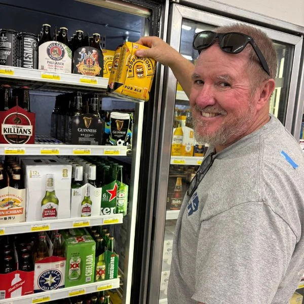 Smiling shopper picking up beer from the cooler at Olsens Marketplace
