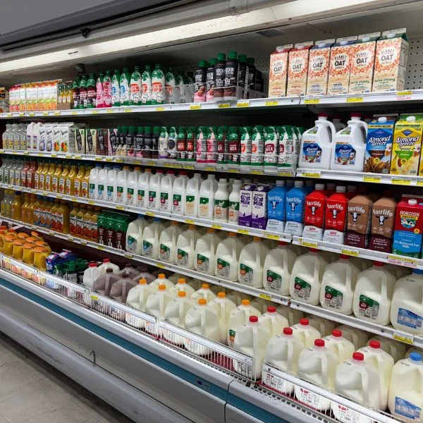 Gallons of milk and bottled juice in the dairy cooler at Olsens Marketplace