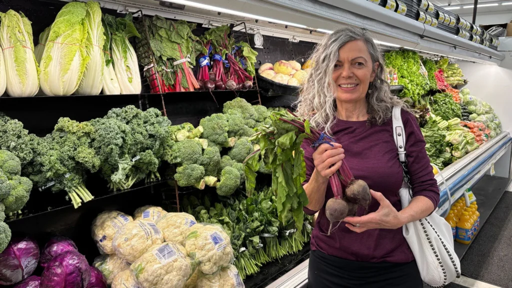 Smiling shopper holding fresh beets in the produce department at Olsens Marketplace