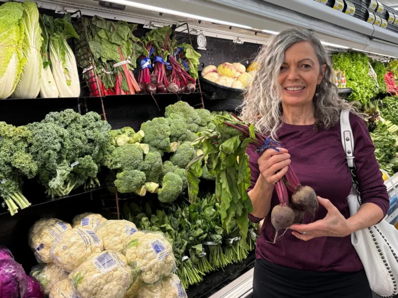 Smiling shopper holding fresh beets in the produce department at Olsens Marketplace