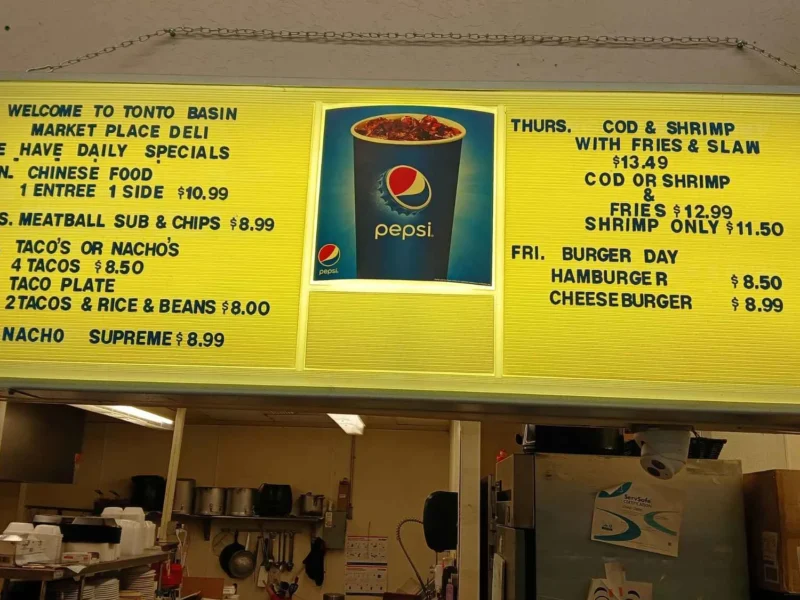 Yellow deli and café menu board listing daily specials, tacos, burgers and fish and chips